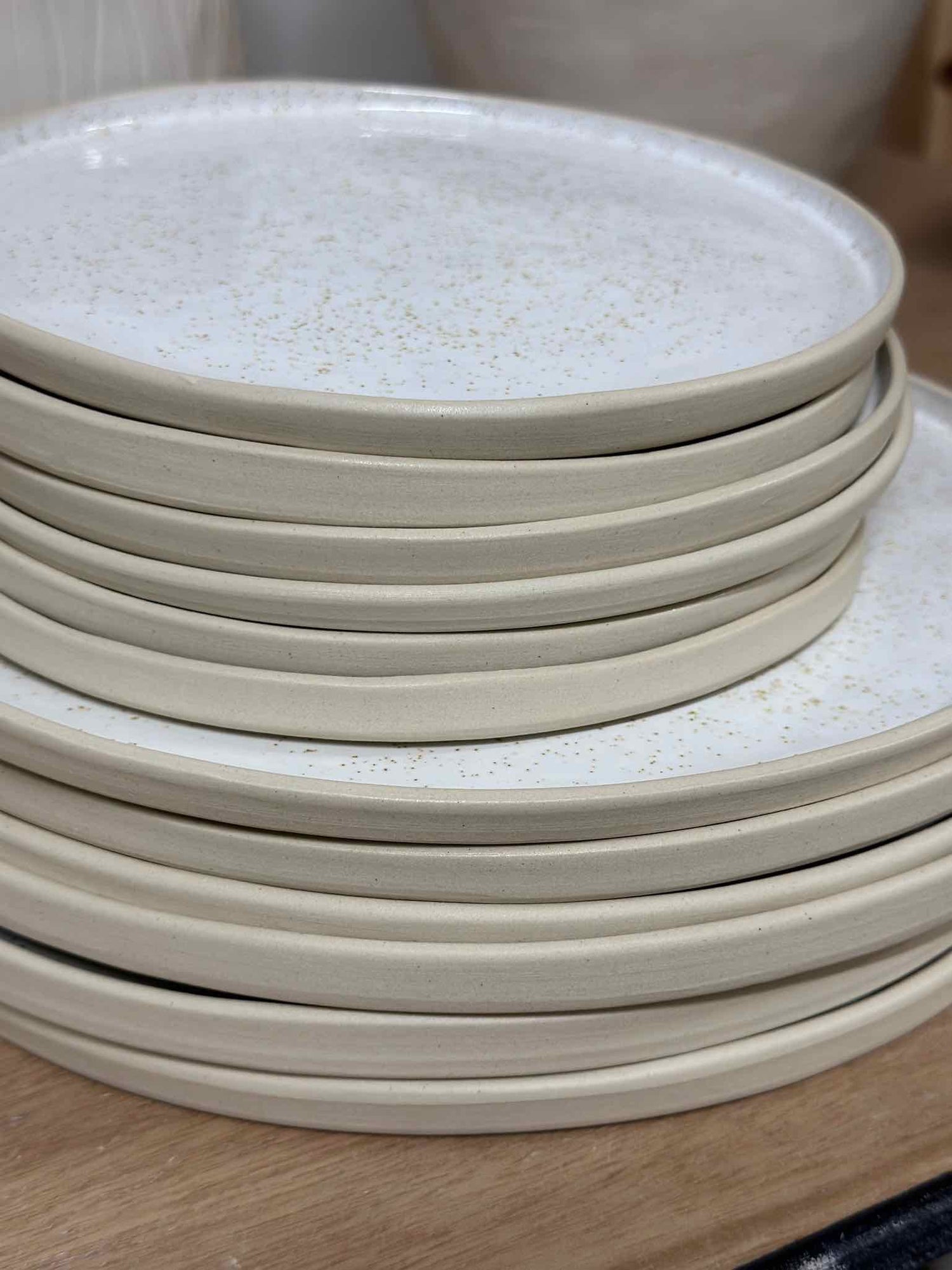 Stack of white clay dinner and side plates in speckled white glaze